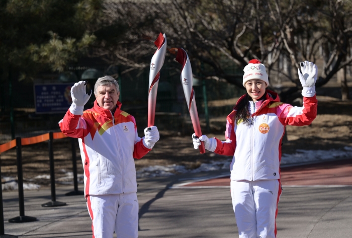 国际奥委会主席巴赫（左）和火炬手张虹进行火炬传递。